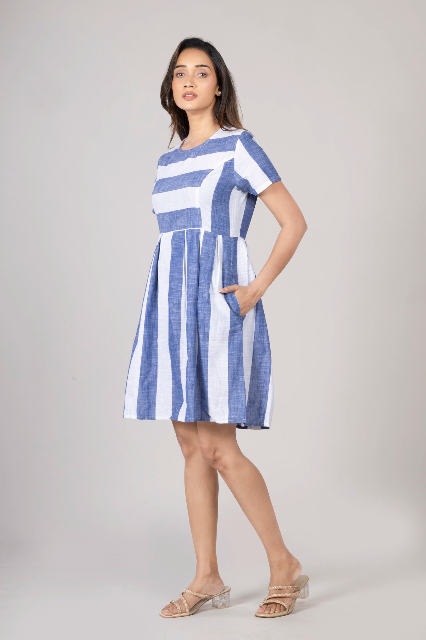 Woman wearing a blue and white striped dress on a gray background